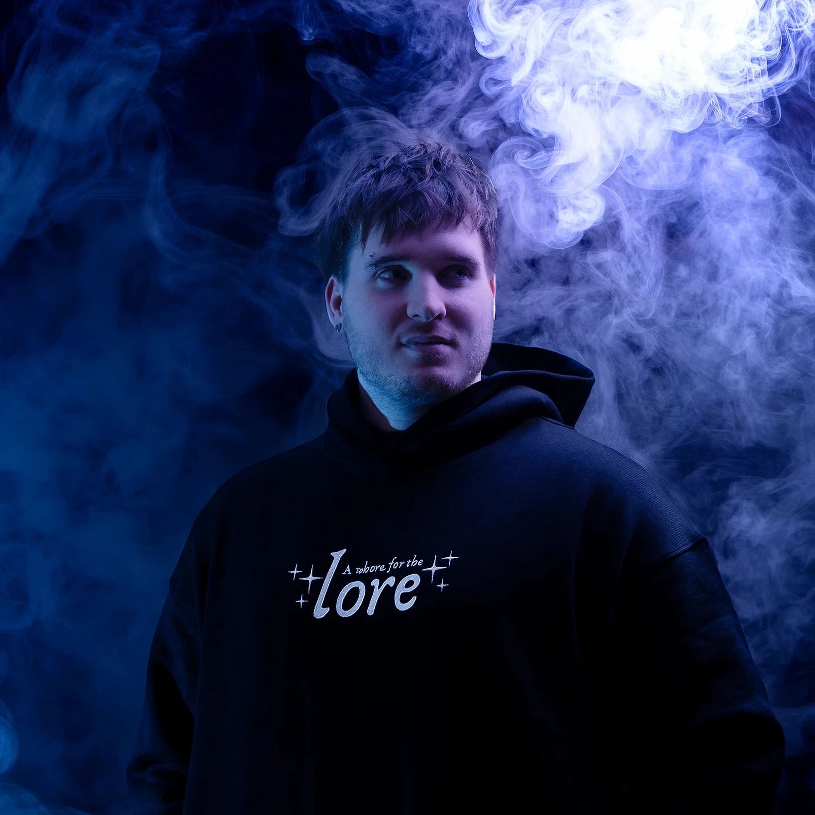 Man wearing black hoodie with text 'a whore for the lore' in white on a purple and blue background